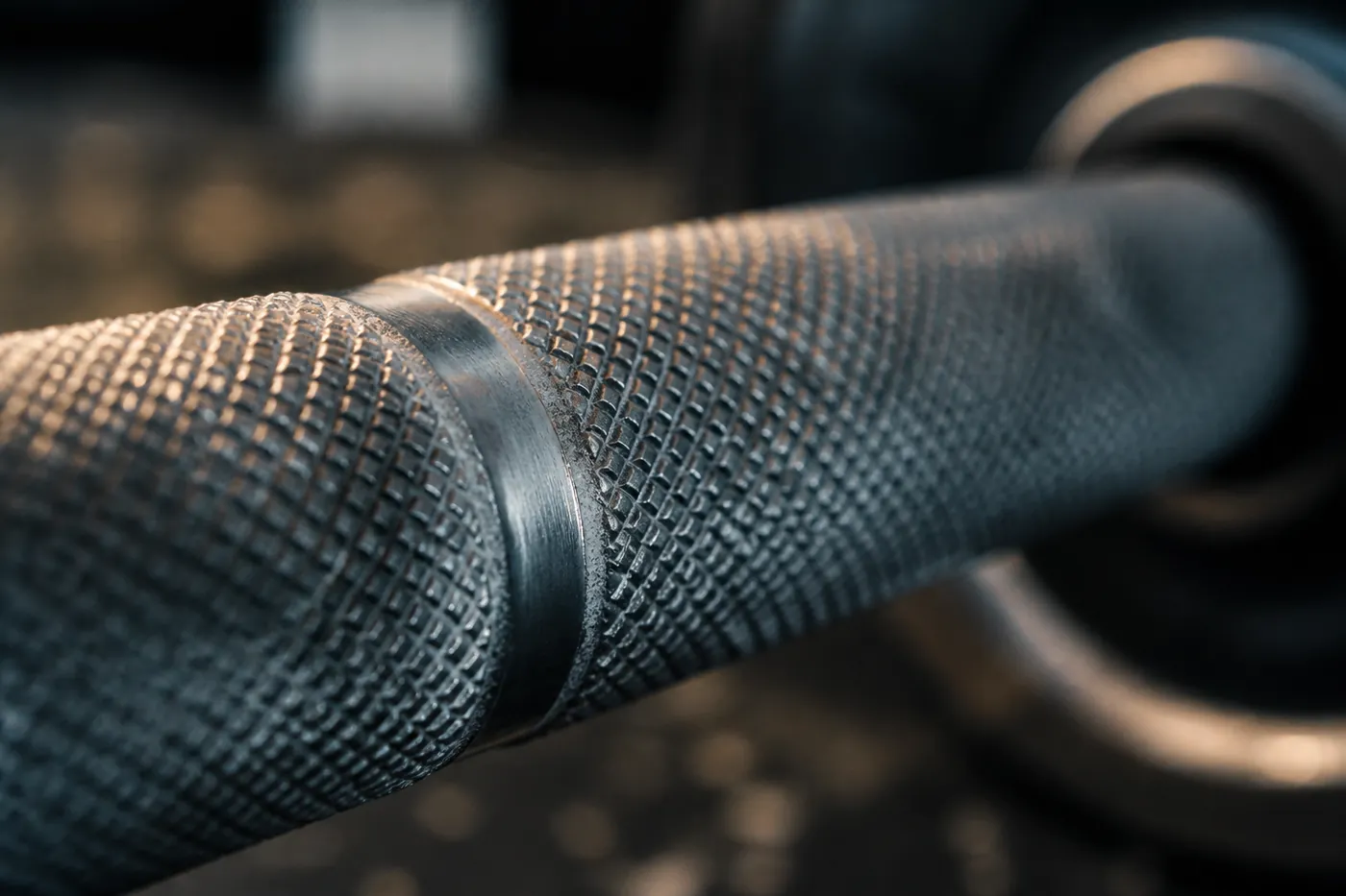 Close view of the knurling and knurl ring on a barbell shaft.